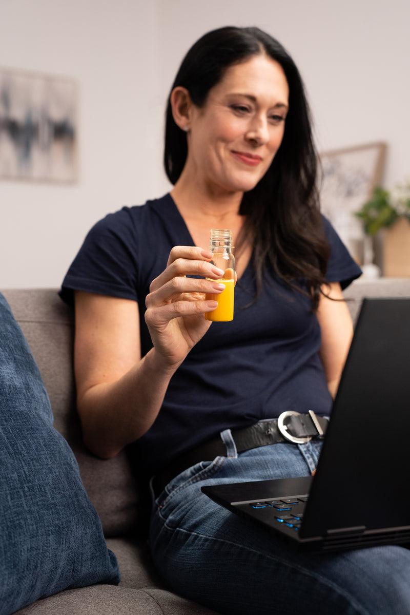 Woman on the couch with her laptop, taking her daily NACPro+ shot